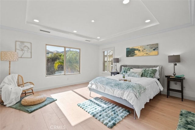 bedroom featuring a tray ceiling, light wood-style flooring, visible vents, and recessed lighting