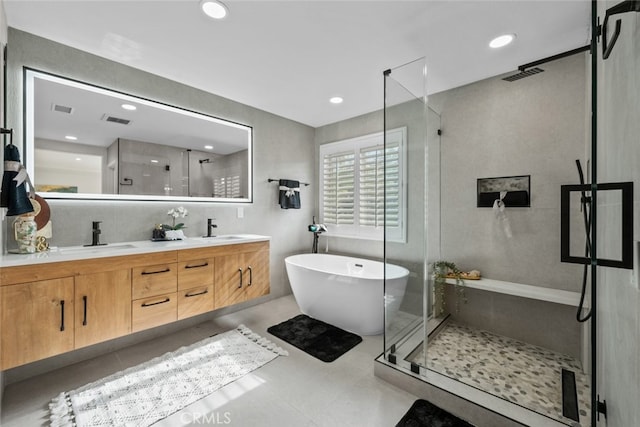 bathroom featuring double vanity, a freestanding tub, a stall shower, and a sink