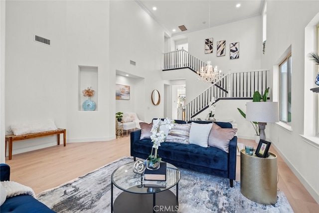 living area with stairs, wood finished floors, a high ceiling, and baseboards