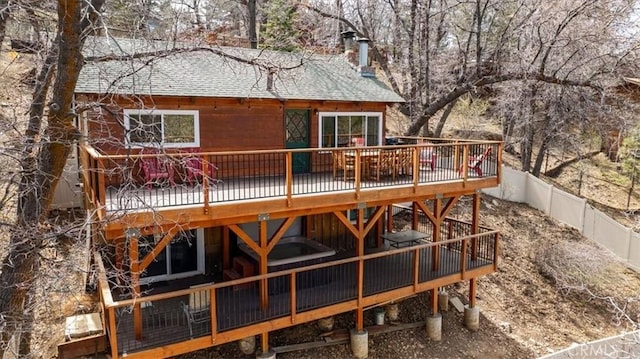 back of house featuring a chimney, roof with shingles, a deck, and a fenced backyard