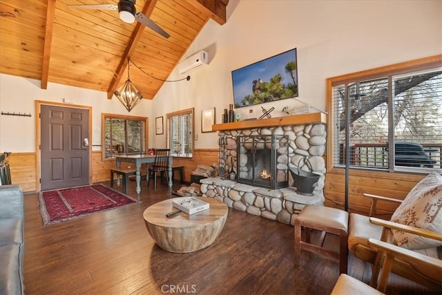 living area with a wainscoted wall, beam ceiling, a wall mounted air conditioner, wood finished floors, and wooden ceiling