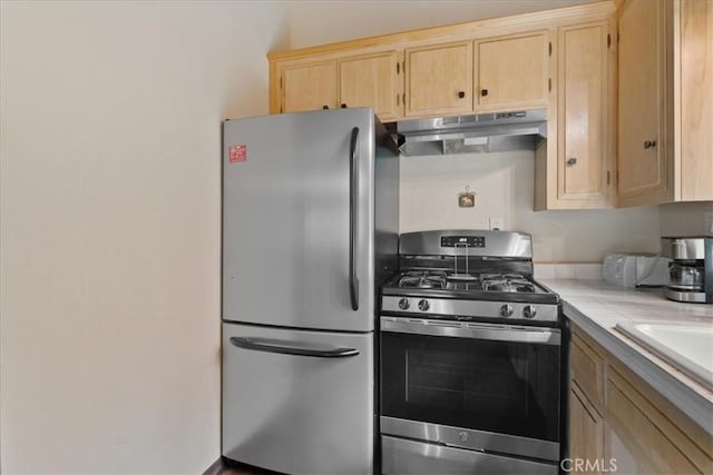 kitchen featuring light brown cabinetry, under cabinet range hood, tile countertops, a sink, and appliances with stainless steel finishes
