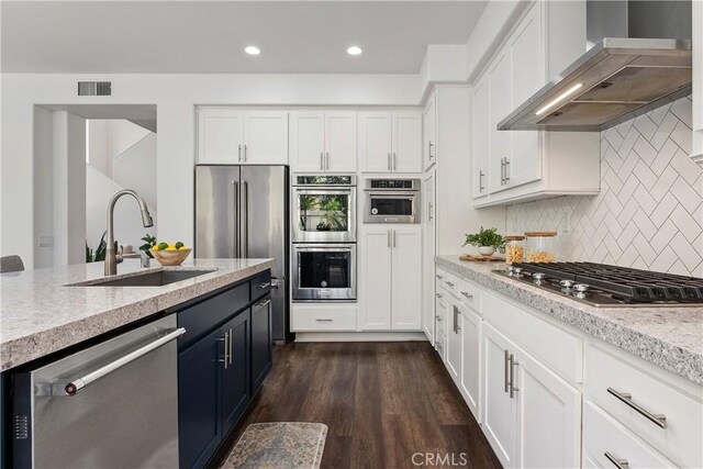 1 Giverny, Newport Coast, CA 92657 - kitchen with appliances with stainless steel finishes, wall chimney exhaust hood, white cabinetry, tasteful backsplash, and recessed lighting