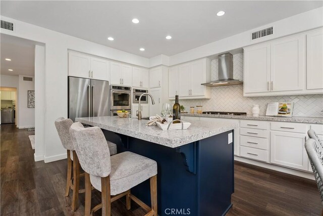 1 Giverny, Newport Coast, CA 92657 - kitchen with wall chimney range hood, stainless steel appliances, backsplash, dark wood-style flooring, and recessed lighting