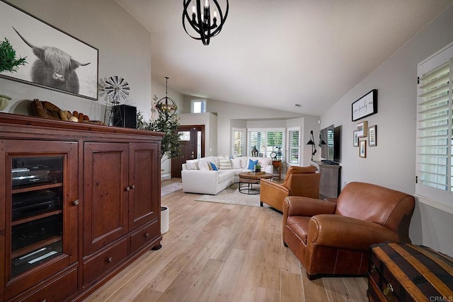 living area with vaulted ceiling, a notable chandelier, and light wood finished floors