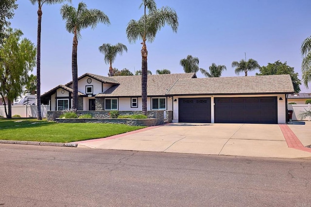 view of front of property with fence, an attached garage, a tile roof, driveway, and a front yard