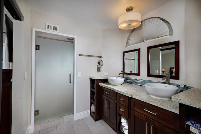 bathroom featuring visible vents, a sink, a shower stall, and double vanity