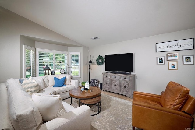 living area with lofted ceiling, visible vents, and light wood-type flooring