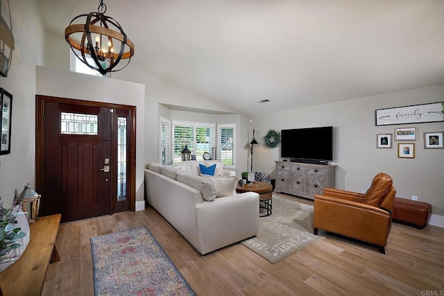 living room with baseboards, lofted ceiling, a chandelier, and light wood-style floors