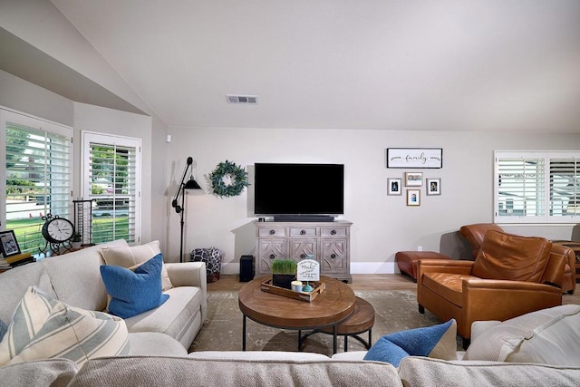 living area featuring lofted ceiling, wood finished floors, visible vents, and baseboards