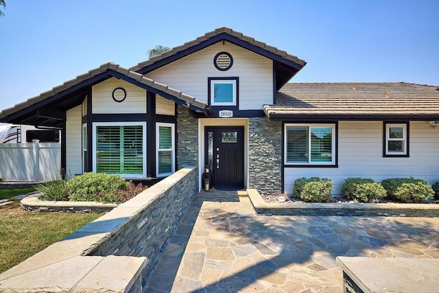 traditional-style home featuring a tile roof and fence