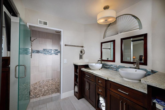 bathroom with a shower stall, a sink, visible vents, and double vanity