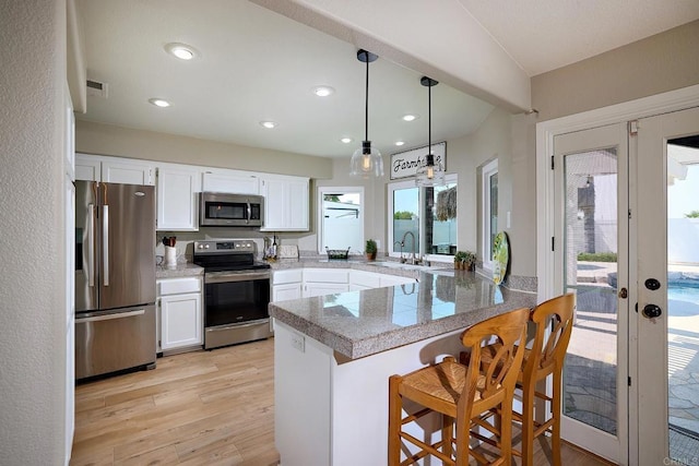 kitchen with stainless steel appliances, a peninsula, french doors, a sink, and tile countertops