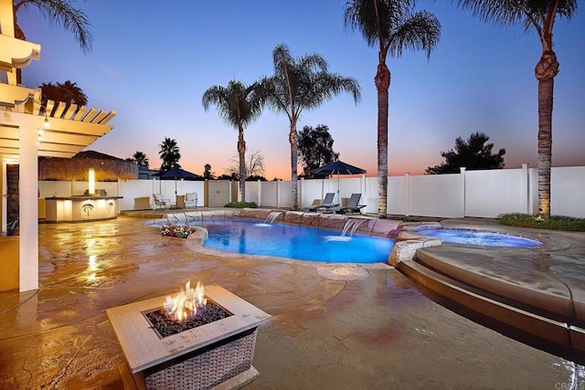 pool at dusk featuring a fenced in pool, a fenced backyard, a patio area, an in ground hot tub, and an outdoor fire pit