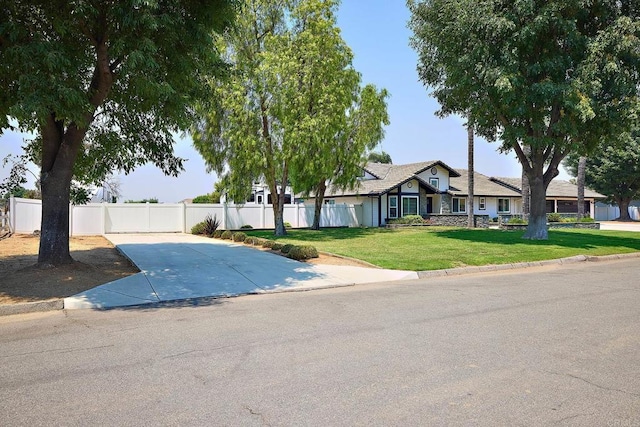 view of front facade with concrete driveway, a front lawn, and fence