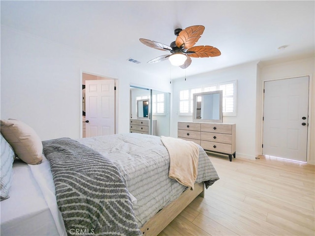 bedroom with a closet, ceiling fan, light wood-type flooring, visible vents, and baseboards