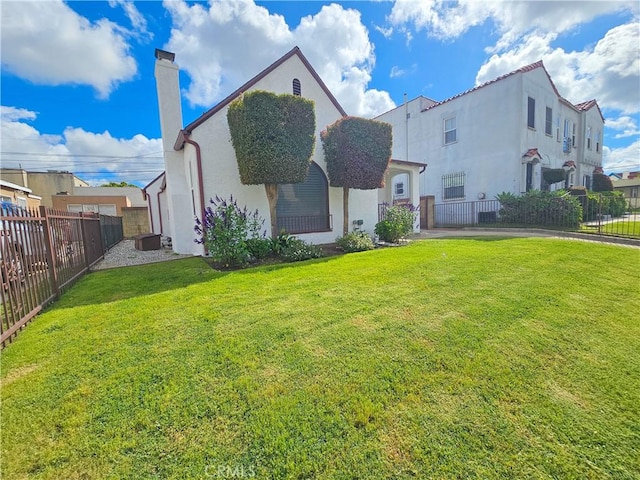 back of house featuring a chimney, fence private yard, and a yard