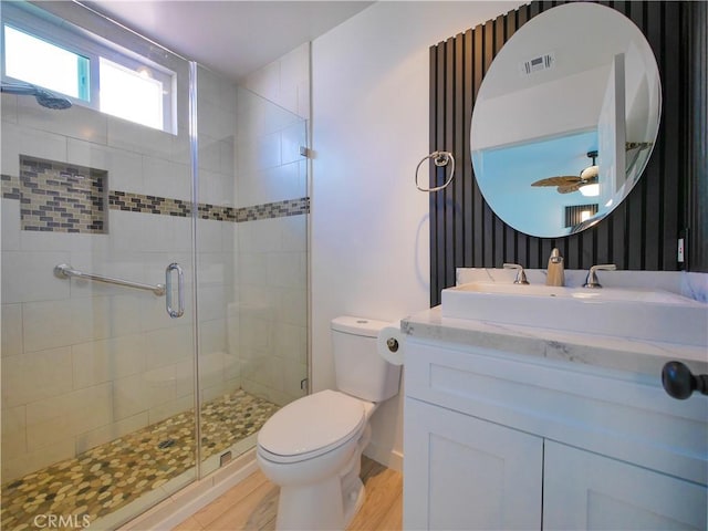 bathroom with a shower stall, toilet, vanity, visible vents, and a ceiling fan
