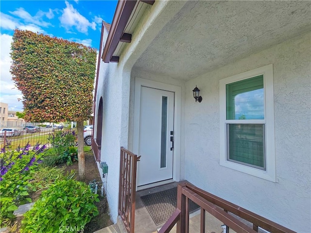 entrance to property with stucco siding and fence