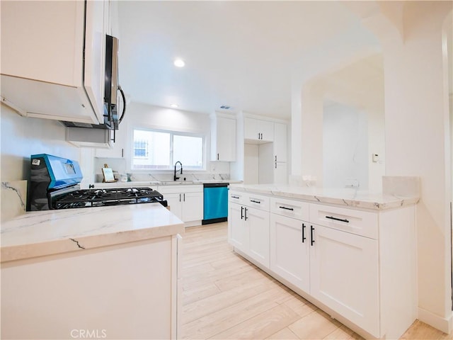 kitchen with white cabinetry, a sink, stainless steel gas stove, light stone countertops, and dishwasher