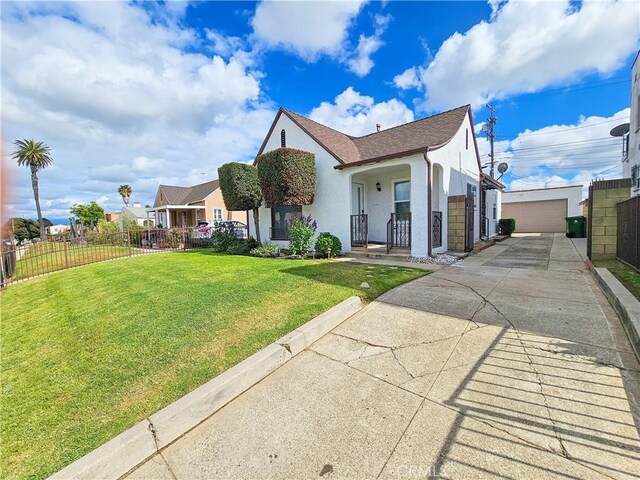 view of front of property featuring a porch, a front yard, a detached garage, stucco siding, and fence
