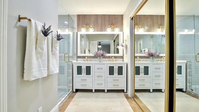 bathroom with a shower stall, double vanity, tile patterned flooring, and a sink