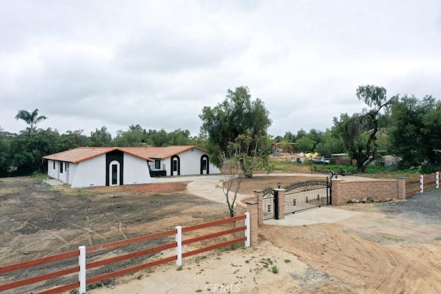 view of front of property with a gate, a tile roof, concrete driveway, fence, and stucco siding