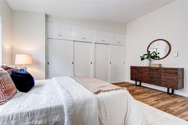 bedroom with baseboards, wood finished floors, and a closet