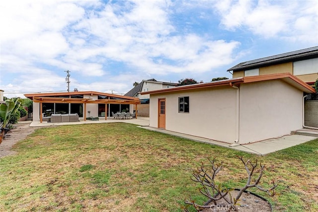 back of house featuring a yard, a patio area, stucco siding, and an outdoor living space