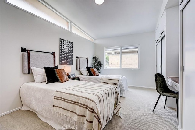 bedroom with baseboards, a closet, and light colored carpet