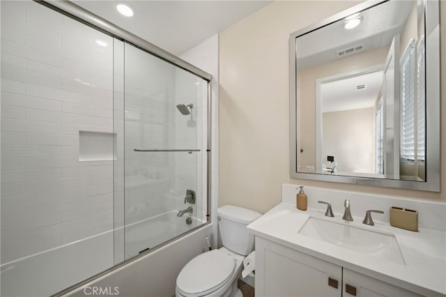 bathroom with toilet, visible vents, enclosed tub / shower combo, and vanity