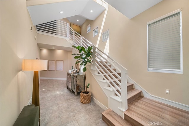 stairs featuring baseboards, recessed lighting, visible vents, and a towering ceiling