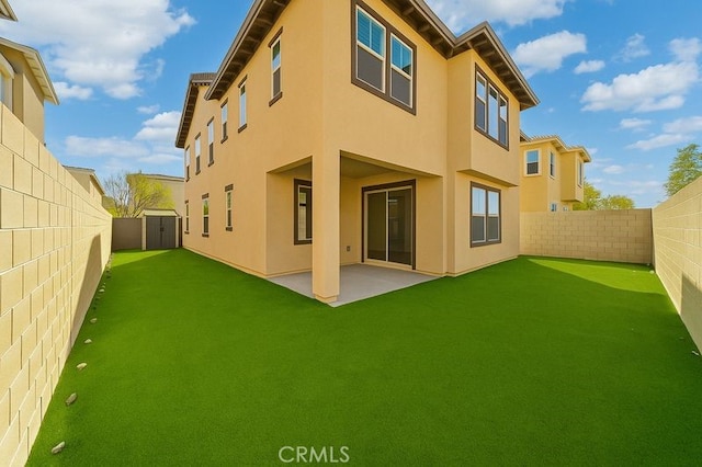 back of property featuring a lawn, stucco siding, a fenced backyard, and a patio area