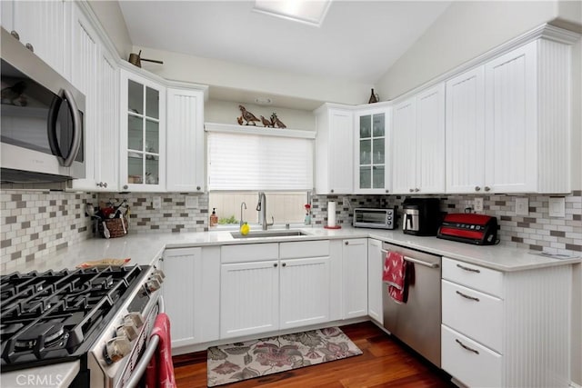 kitchen featuring white cabinetry, appliances with stainless steel finishes, decorative backsplash, and a sink
