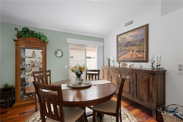 dining space with wood finished floors, visible vents, and vaulted ceiling