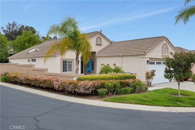 view of front of home with concrete driveway, a tiled roof, stucco siding, fence, and a garage