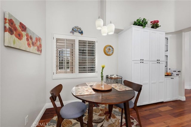 dining area featuring a high ceiling, baseboards, and dark wood-type flooring