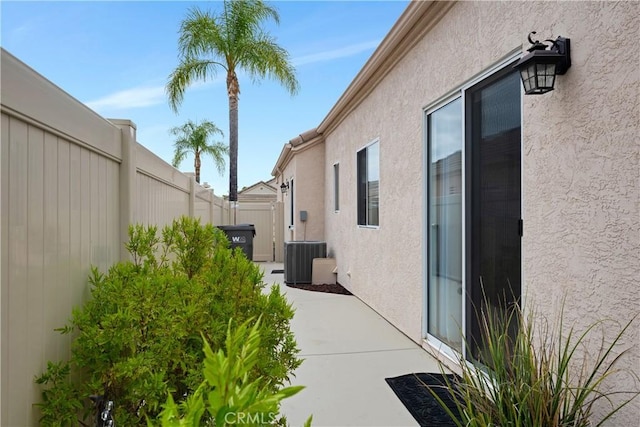 view of property exterior featuring a patio, central AC unit, stucco siding, and fence