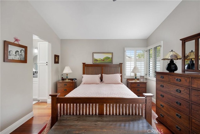 bedroom featuring lofted ceiling, wood finished floors, and baseboards