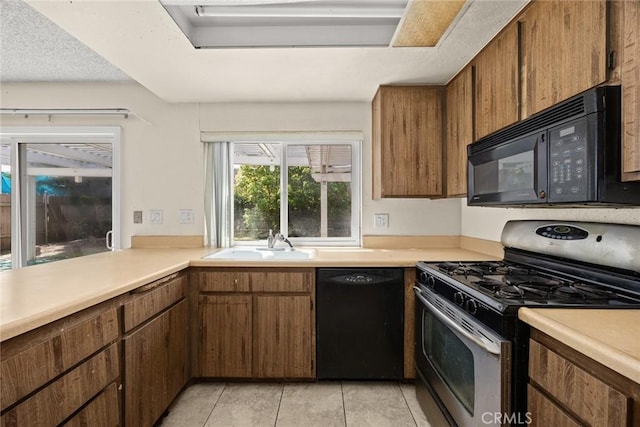 kitchen featuring light countertops, a sink, and black appliances