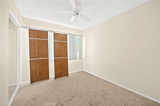 unfurnished bedroom with ceiling fan, baseboards, a textured ceiling, and carpet
