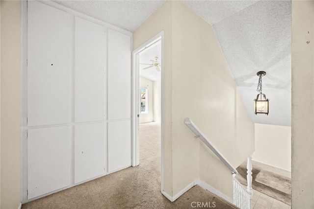 stairway with lofted ceiling, baseboards, and a textured ceiling