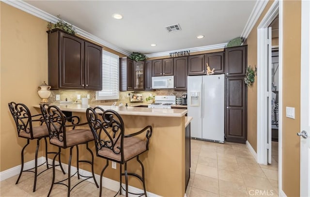 1765 Desert Poppy Ln, Beaumont, CA 92223 - kitchen featuring white appliances, a peninsula, dark brown cabinetry, decorative backsplash, and crown molding