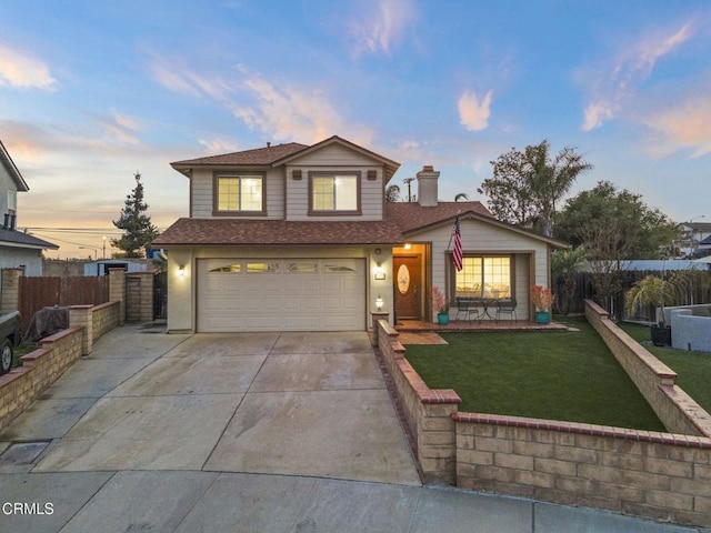 traditional-style house featuring concrete driveway, an attached garage, fence, and a lawn