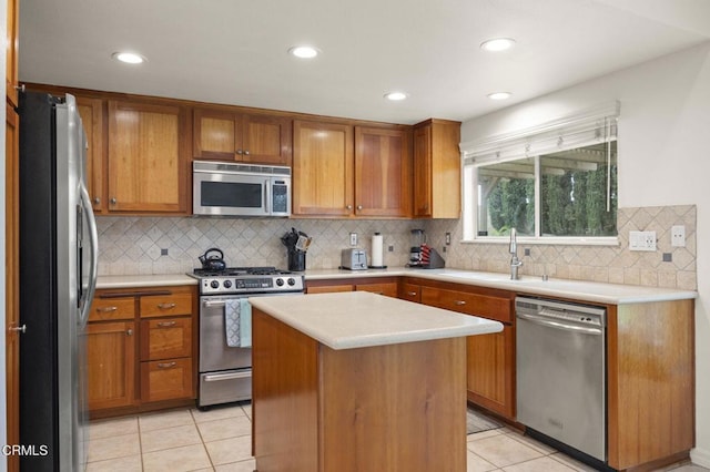 kitchen featuring stainless steel appliances, light countertops, a sink, light tile patterned flooring, and brown cabinetry