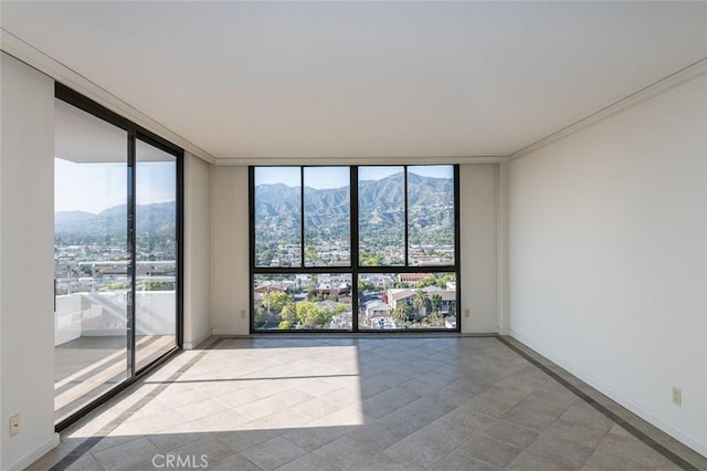 tiled empty room featuring crown molding, expansive windows, baseboards, and a mountain view