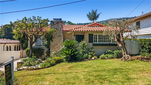 view of front facade featuring stucco siding, fence, a tiled roof, and a front yard