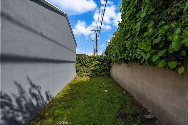 view of side of home featuring a lawn and fence