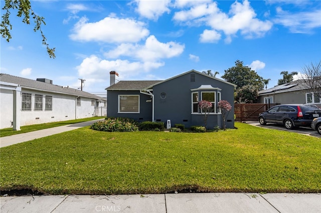bungalow-style home featuring fence, a chimney, a front yard, and stucco siding