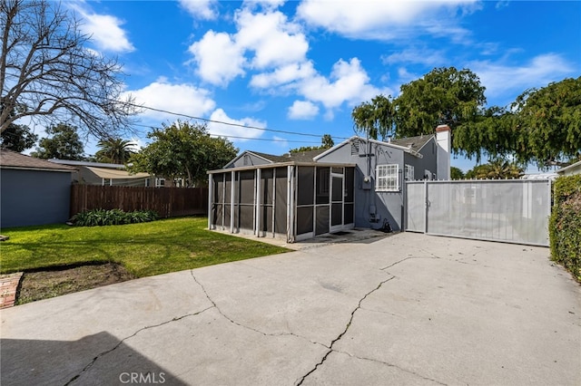 back of property featuring a lawn, fence, a patio, stucco siding, and a sunroom